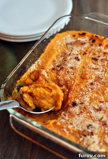 Top view of a clear casserole dish showcasing the smooth, creamy texture of the sweet potato casserole.