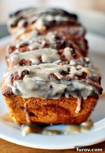 Glazed slices of pumpkin pull-apart bread arranged beautifully on a white plate, highlighting its soft, layered texture and warm autumn hues.