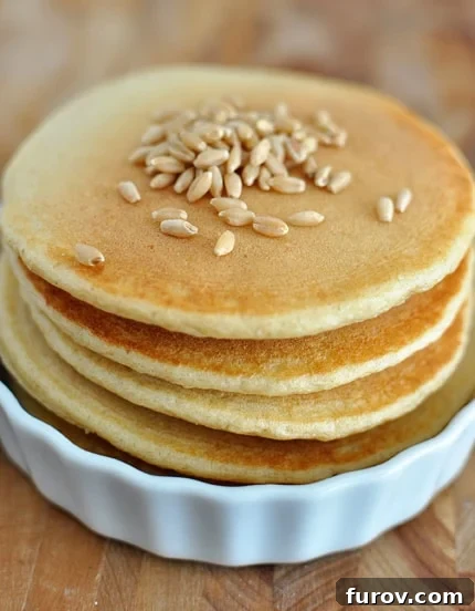 Blender Brilliance: Wholesome Whole Wheat Pancakes 2 A stack of wheat pancakes in a white ramekin, with wheat berries scattered on the top pancake.