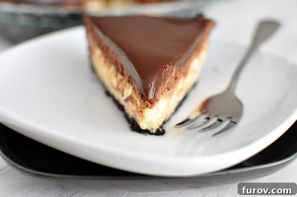 A pristine slice of chocolate crust cheesecake pie generously topped with a decadent chocolate ganache, beautifully presented on a white plate.