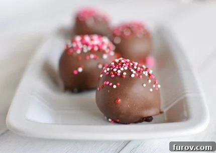 Chocolate-dipped and sprinkle-topped brownie truffles arranged elegantly on a pristine white dish, ready to be devoured.