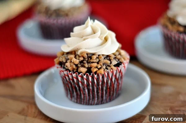 Golden Toffee Crunch Cupcakes 2 A toffee and frosting topped chocolate cupcake in a small white dish, showcasing its rich ganache and caramel frosting.
