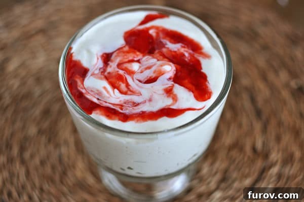 Top view of a glass goblet of creamy homemade yogurt with a vibrant raspberry swirl inside, ready to be enjoyed.