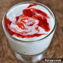 A vibrant raspberry swirl within a glass of homemade yogurt