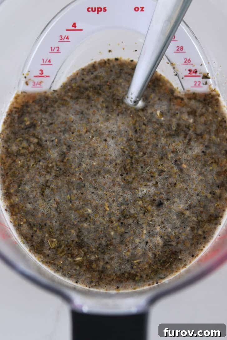 Melt-in-Your-Mouth Slow Cooker Italian Beef 3 Liquid measuring cup with beef broth, dried oregano, dried basil, and dried thyme seasonings, ready for mixing.
