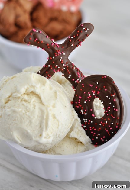 White bowl with vanilla ice cream topped with chocolate sprinkled X and O nestled in the ice cream.