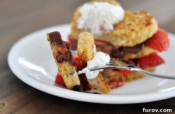 Close-up of a chocolate and strawberry stuffed french toast with a fork taking a bite out, revealing the creamy filling.