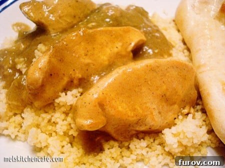 Succulent chicken slices generously coated in a vibrant green curry sauce, served atop fluffy white couscous.