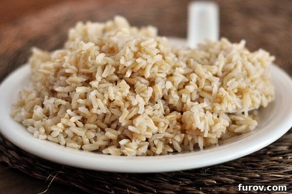 A white plate piled high with perfectly cooked, fluffy brown rice.