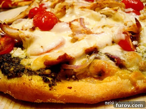 Side view of a freshly baked pesto pizza with a golden-brown crust and melted cheese.