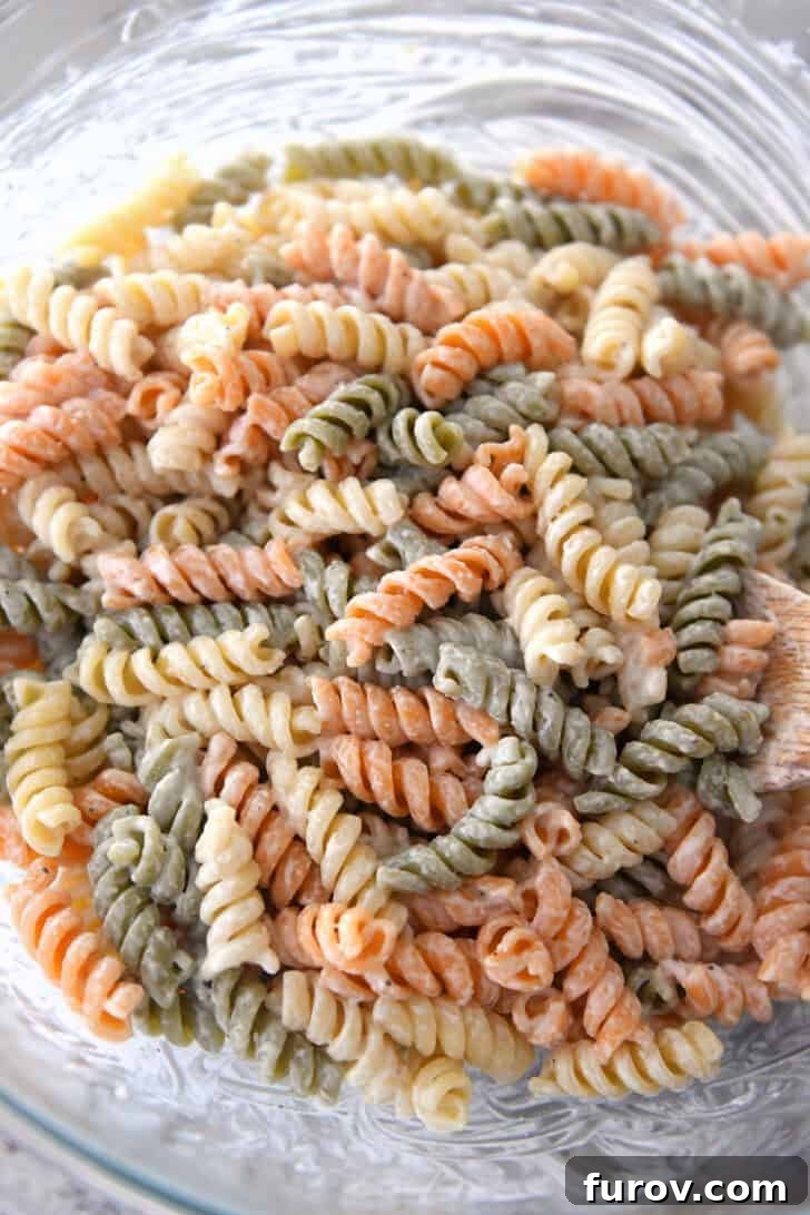 Vibrant Tricolor Pasta Medley 4 Top down view of caesar dressing-coated tri-color pasta in glass bowl.