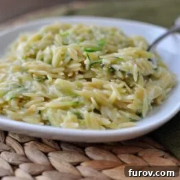Close-up of Toasted Orzo with Peas and Parmesan, garnished with herbs.
