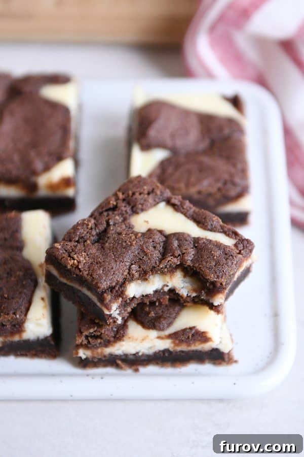 Ebony and Ivory Cheesecake Brownies 2 Stack of black and white cheesecake brownies with bite taken out of top.
