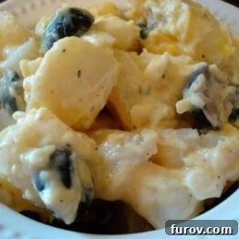A close-up of a white bowl filled with the creamy, perfect potato salad, showcasing its rich texture and inviting appearance.