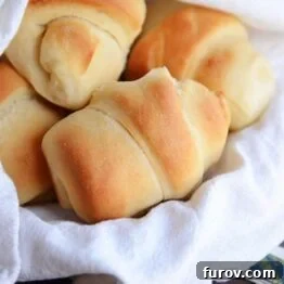 A close-up of a plate of Make-Ahead Buttermilk Dinner Rolls, highlighting their golden crust.