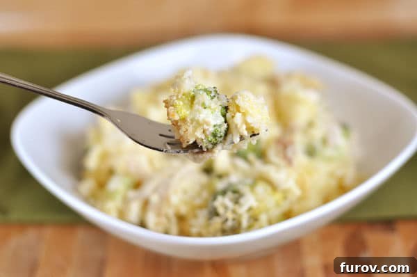 A serving of the delicious homemade broccoli cheese casserole in a white dish, showcasing its gooey cheese and vibrant broccoli.