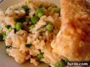 A serving of chicken and rice with peas on a white plate, highlighting the delicious texture.