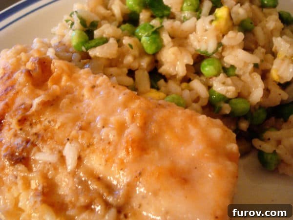 Plated chicken with a side of creamy coconut rice and green peas, ready to be enjoyed.
