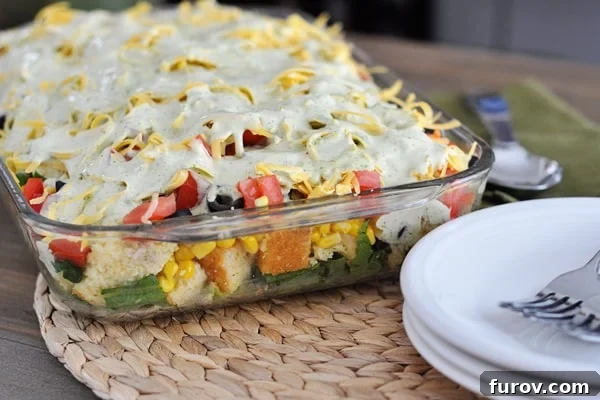 Glass 9x13 dish with a vibrant layered cornbread salad, showcasing distinct layers of fresh ingredients.