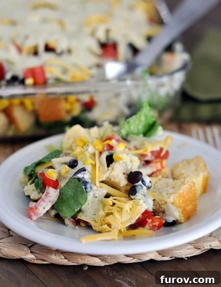 A white plate with a generous helping of colorful Mexican cornbread salad, ready to be enjoyed.