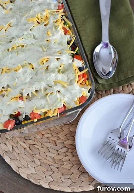 Top view of a glass 9x13 inch dish with a finished cornbread salad, generously sprinkled with cheese and dressing.