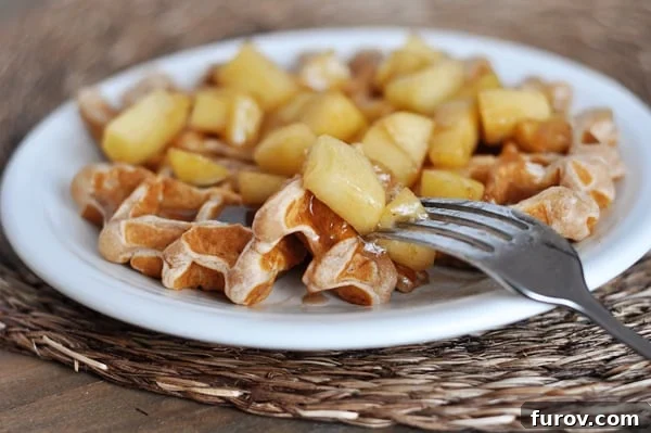 Warm Spiced Apple Waffles with Cinnamon Drizzle 3 Close-up of an apple cinnamon covered waffle on a white plate, highlighting the delicious topping.