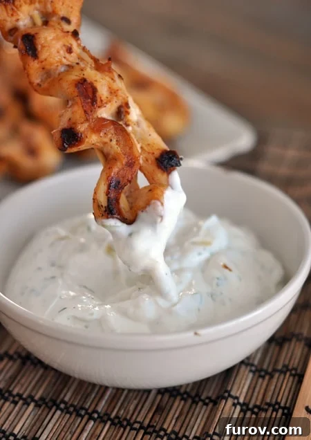 Smoky Chipotle Chicken Skewers with Zesty Avocado Crema 3 A perfectly grilled chipotle chicken skewer being generously dipped into a creamy, vibrant sauce.