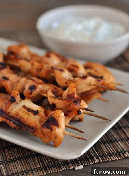 Smoky Chipotle Chicken Skewers with Zesty Avocado Crema 4 White platter laden with grilled chipotle chicken skewers, with a bowl of the creamy dipping sauce prominently displayed behind them.