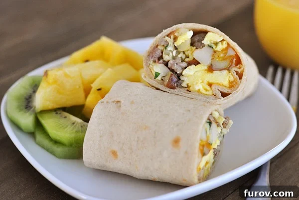 Morning Fuel Wraps 3 A second view of a breakfast burrito split in half on a white plate, accompanied by fresh pineapple and kiwi.