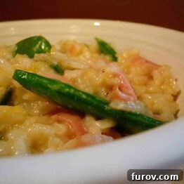 White bowl of risotto with sugar snap peas and ham.