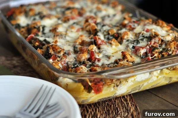 A 9x13 inch glass baking dish brimming with golden-baked Pesto Sausage Baked Ziti, fresh from the oven.