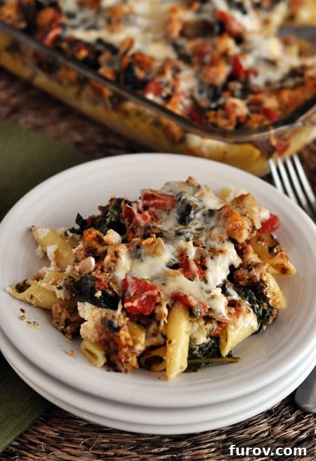 A close-up shot of Pesto and Sausage Baked Ziti on a white plate, showcasing its rich texture and ingredients.