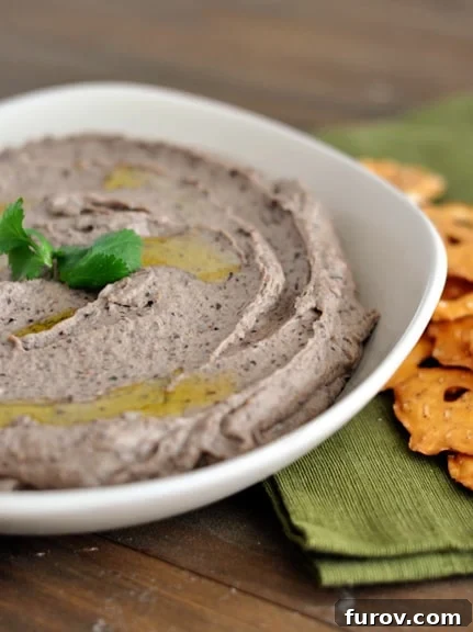 Zesty Black Bean Dip 2 A beautifully presented white bowl full of creamy black bean hummus, garnished with fresh cilantro and a drizzle of olive oil, ready for dipping.