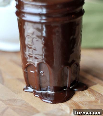 Velvety Hot Fudge Sauce 3 A glass jar overflowing with rich, homemade hot fudge sauce