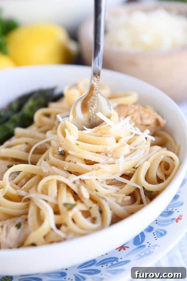 Twisting pasta in white dish around fork. A close-up shot of Beach Street Lemon Chicken Pasta, showing tender chicken strips and vibrant green herbs intertwined with golden linguine, ready to be enjoyed.