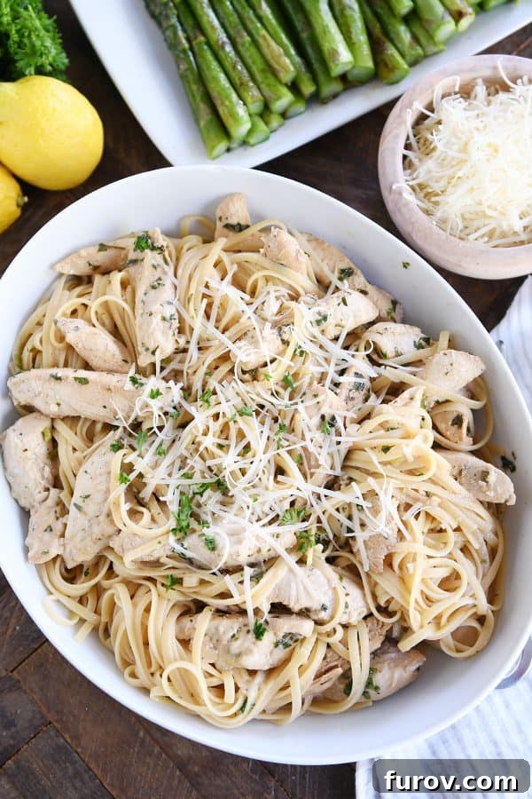 Top down view of lemon chicken pasta in white dish, garnished with fresh parsley and lemon slices. The dish is inviting, showcasing the rich colors of the ingredients.