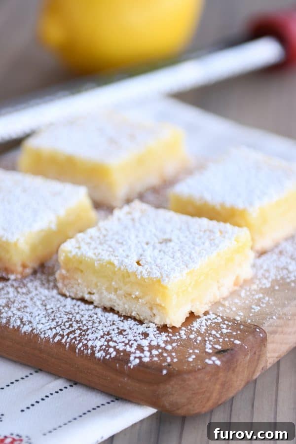 Lemon bars on cutting board sprinkled with powdered sugar.