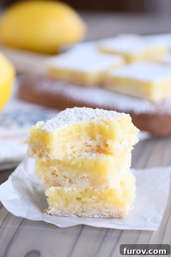 The best lemon bars stacked on each other and bite taken out of top lemon bar.