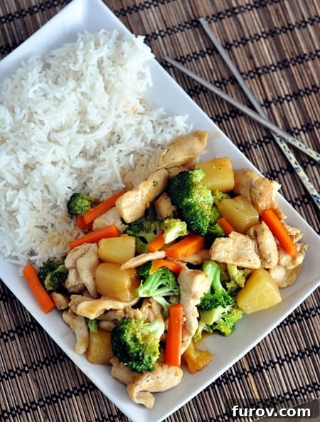 A white rectangular platter with cooked white rice on one side and chicken stir fry on the other.