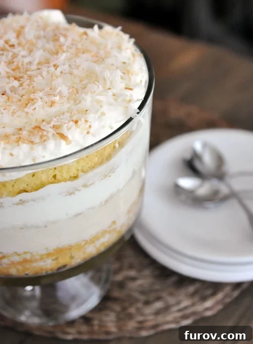 Decadent Coconut Tres Leches Trifle 2 A beautiful trifle dish brimming with layers of Coconut Tres Leches Cake Trifle, generously topped with golden toasted coconut.