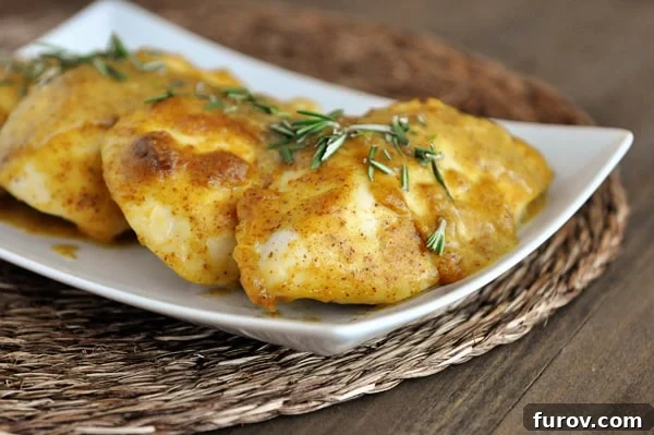 Tender baked chicken breasts generously coated in a shimmering sweet mustard glaze, served in a pristine white baking dish, ready to be enjoyed.