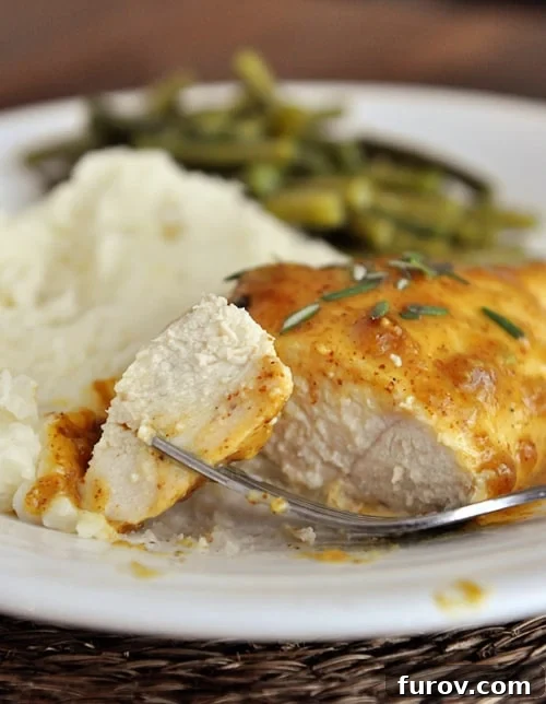 A succulent piece of sweet mustard baked chicken, with a bite taken, alongside creamy mashed potatoes and vibrant green beans on a white plate, showcasing a perfect weeknight meal.