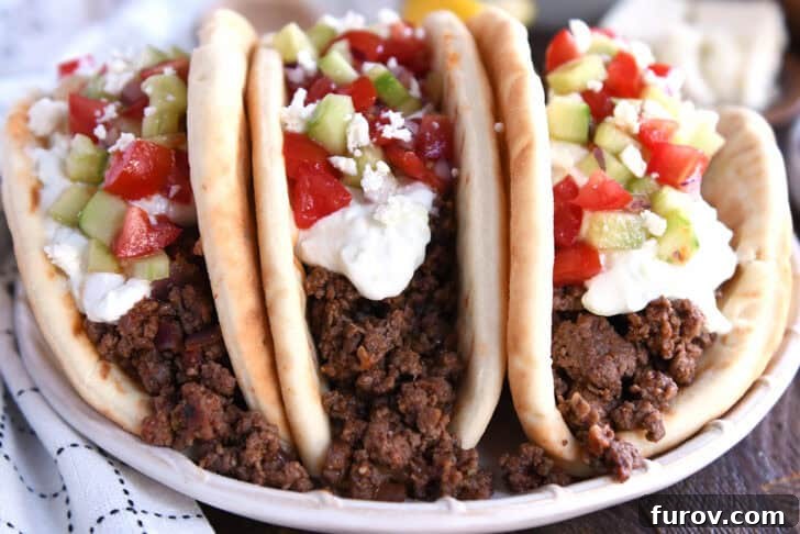 Olympian Taco Feast 3 Front view of three beautifully stuffed Greek flatbread tacos, showcasing the generous toppings of creamy tzatziki sauce, crisp chopped cucumbers, and vibrant diced tomatoes, ready to be enjoyed.
