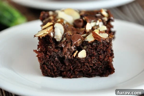 A slice of moist chocolate zucchini cake topped with crunchy brown sugar streusel, served on a white plate, ready to be enjoyed.