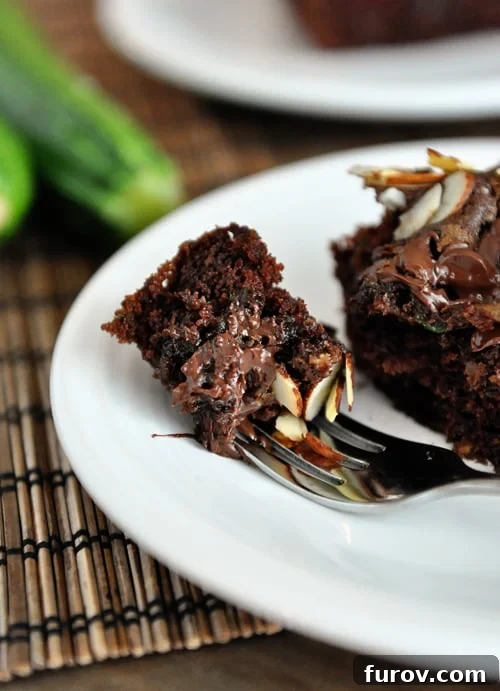 A delectable chocolate zucchini cake with a bite taken out, showcasing its moist interior and tempting streusel topping.