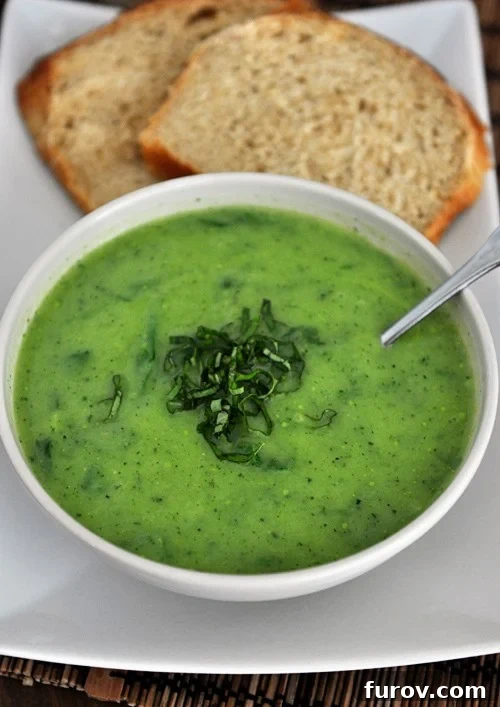 A bowl full of vibrant green basil spinach soup next to two pieces of golden toast, ready to be enjoyed.
