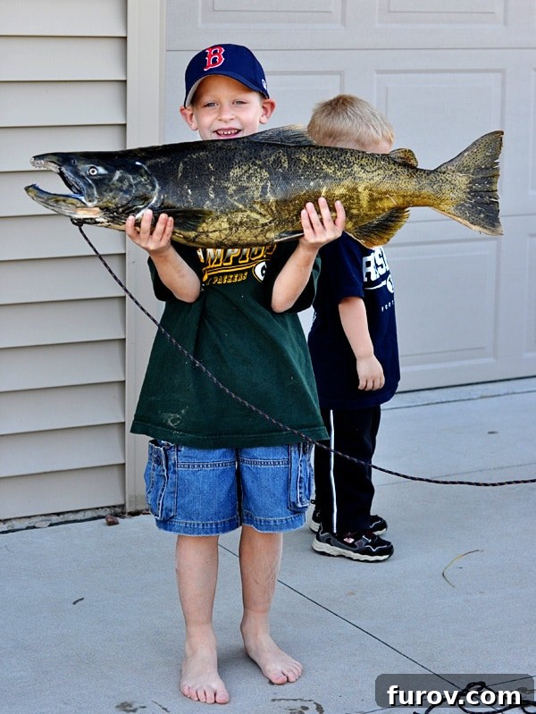 a young boy proudly holding a remarkably large fish, beaming with excitement and a sense of accomplishment