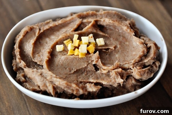 White oval bowl full of refried beans.