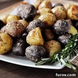 Close-up of golden brown salt-crusted potatoes with fresh rosemary, ready to serve.