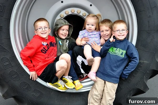 five little kids sitting inside the rim of a giant tire